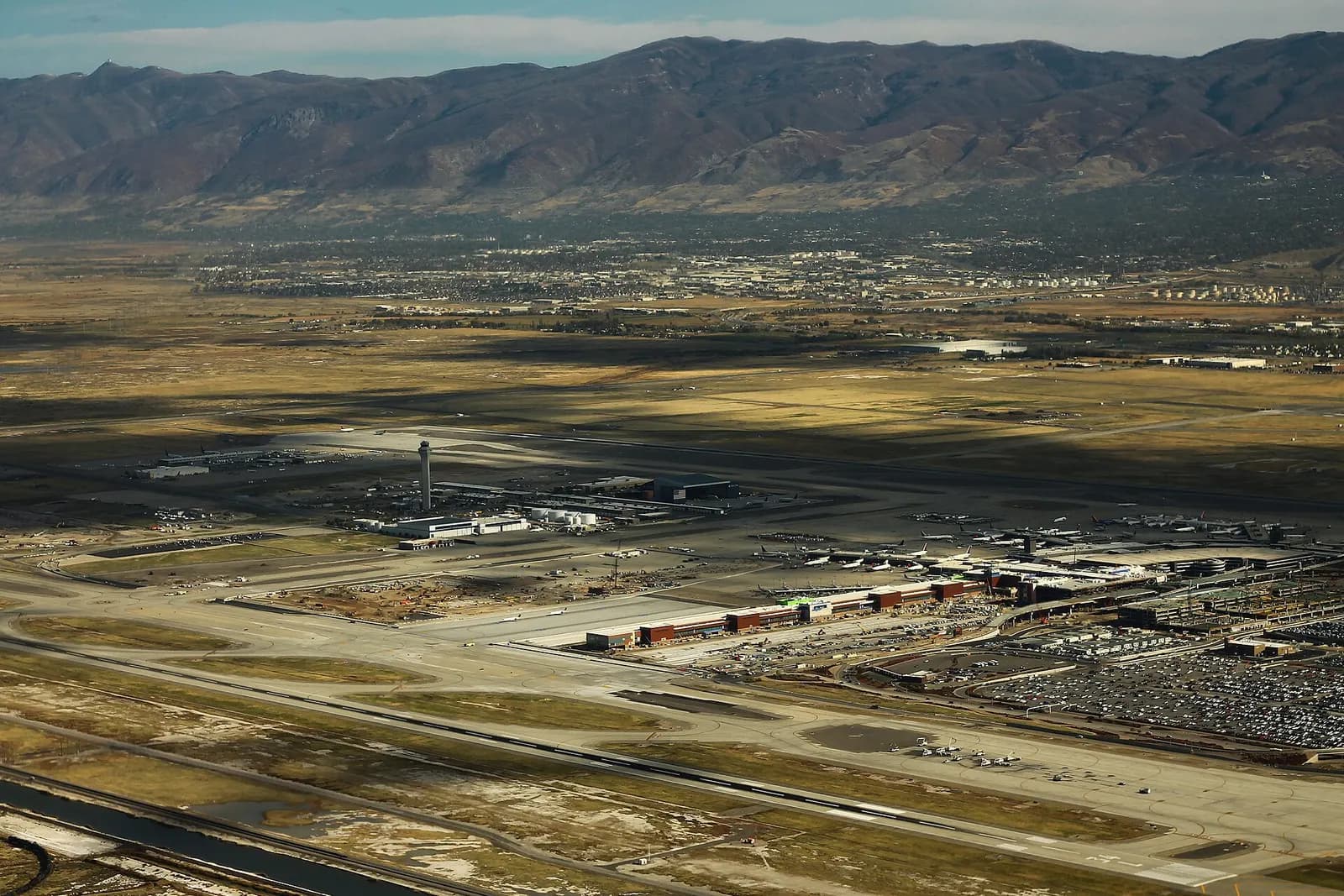 Aerial photograph of Salt Lake City International Airport showing runways, terminals, and the flat terrain around the airfield.