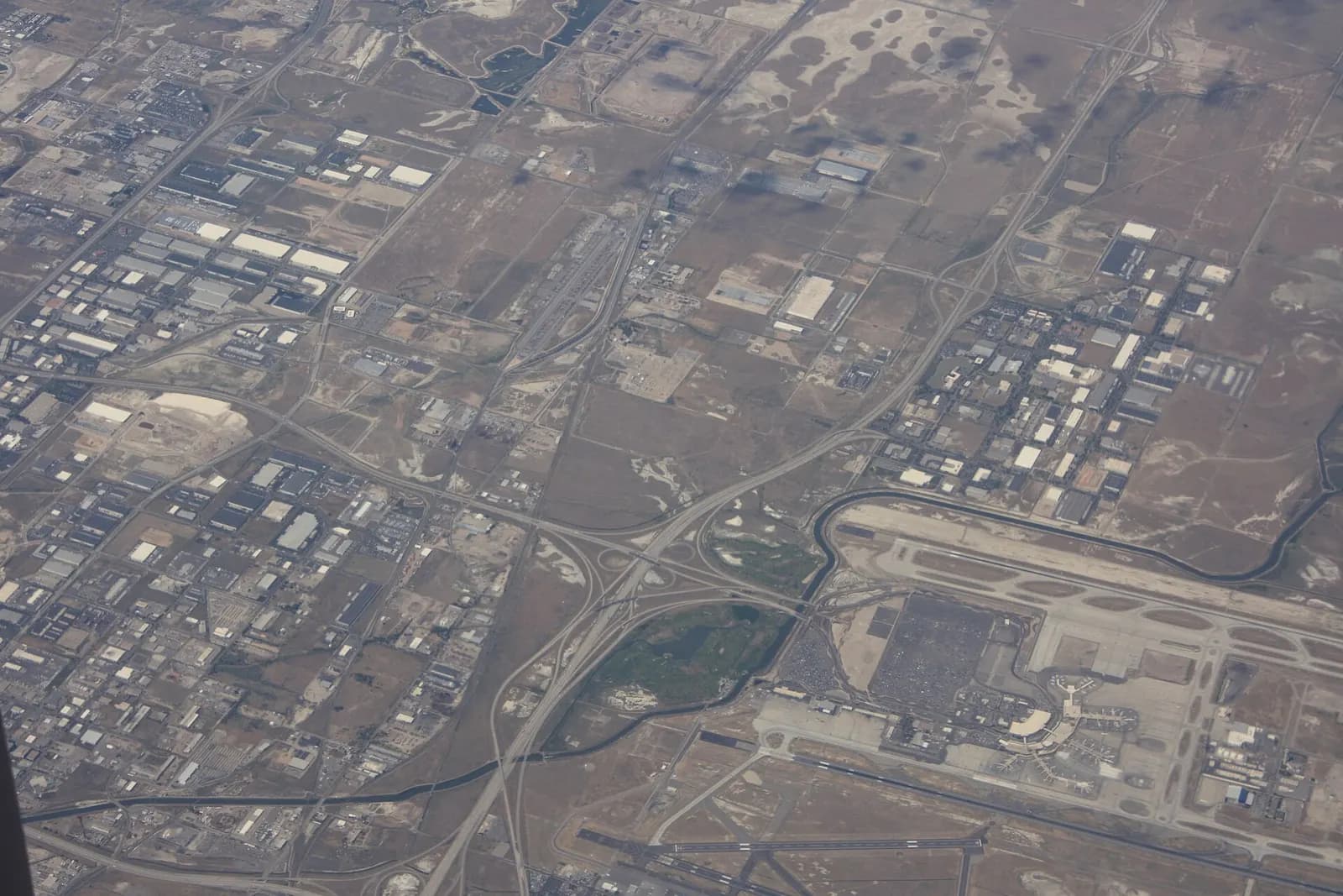 View from an airplane window showing Salt Lake City International Airport beside a golf course and a highway interchange.