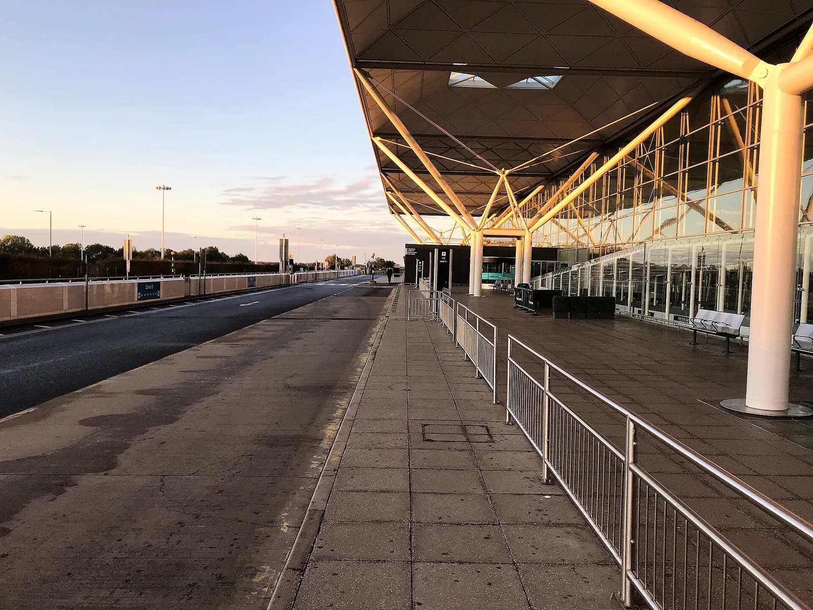 An empty check-in and departures concourse inside London Stansted Airport with airline counters and high ceilings.