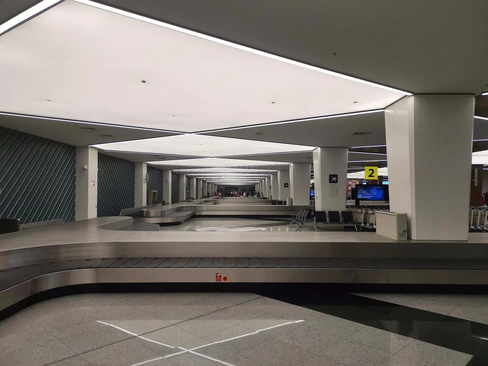 Baggage reclaim area in Terminal C with a curved luggage carousel, arrival signage, and a high open ceiling.