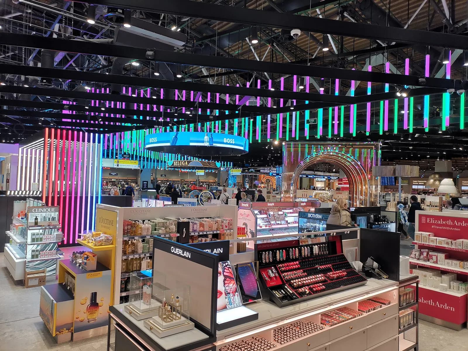 Duty-free shopping corridor in Terminal C with brightly lit storefronts and travelers browsing retail displays.