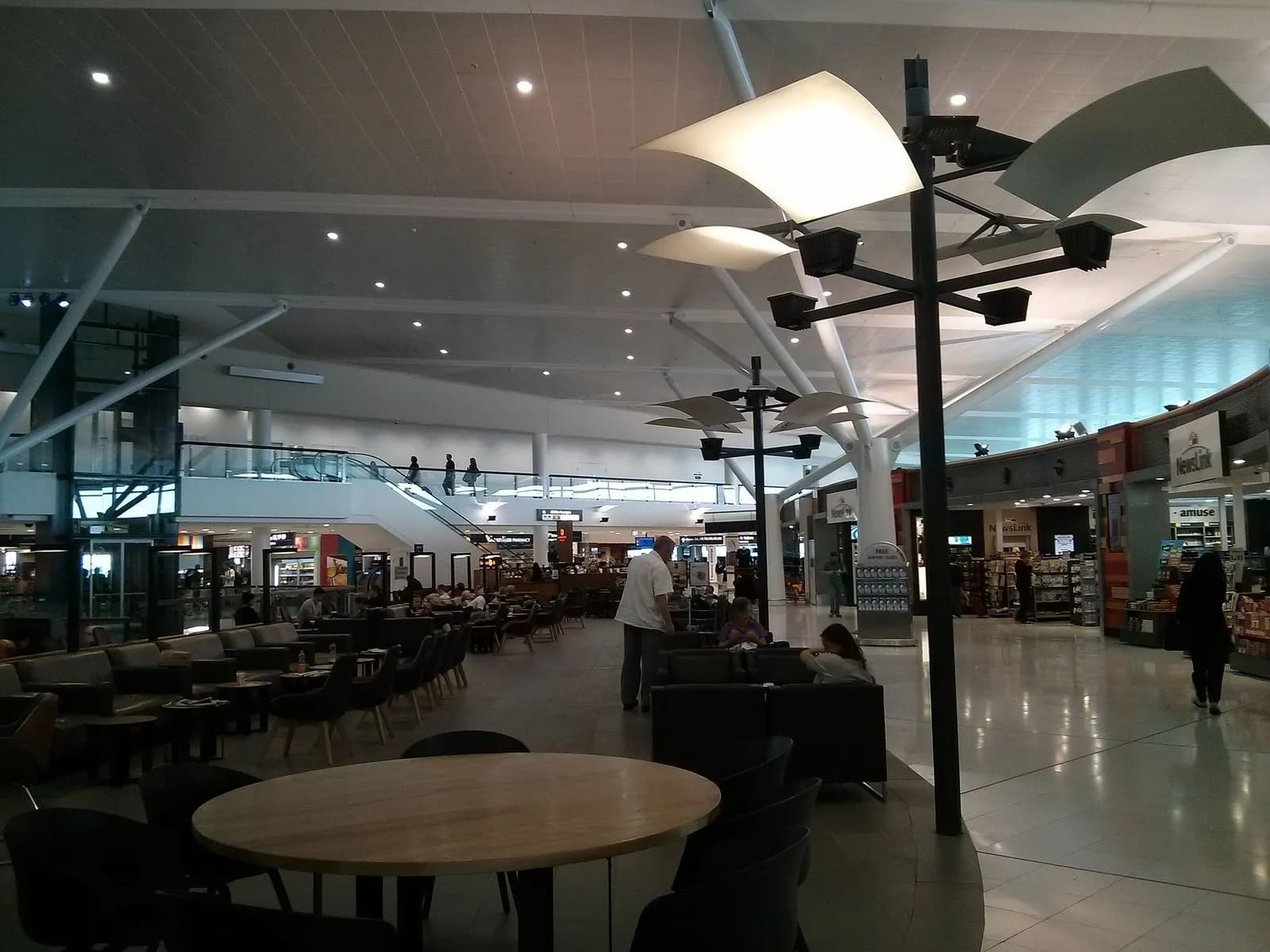 Passengers walk through the bright, high-ceilinged departures concourse inside Sydney Airport's international terminal.