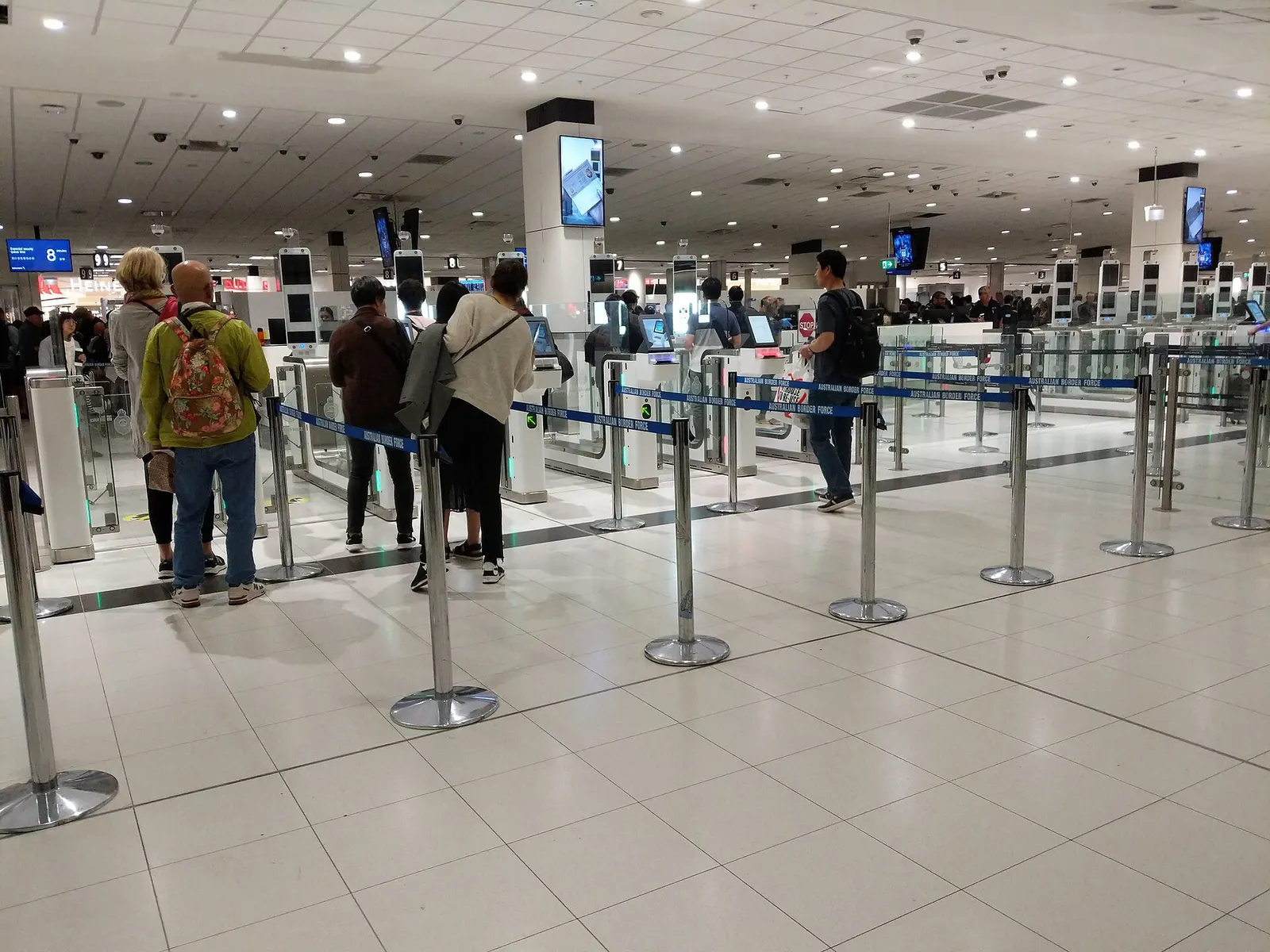 Automated SmartGate ePassport kiosks stand in rows inside Sydney Airport's departures immigration area.