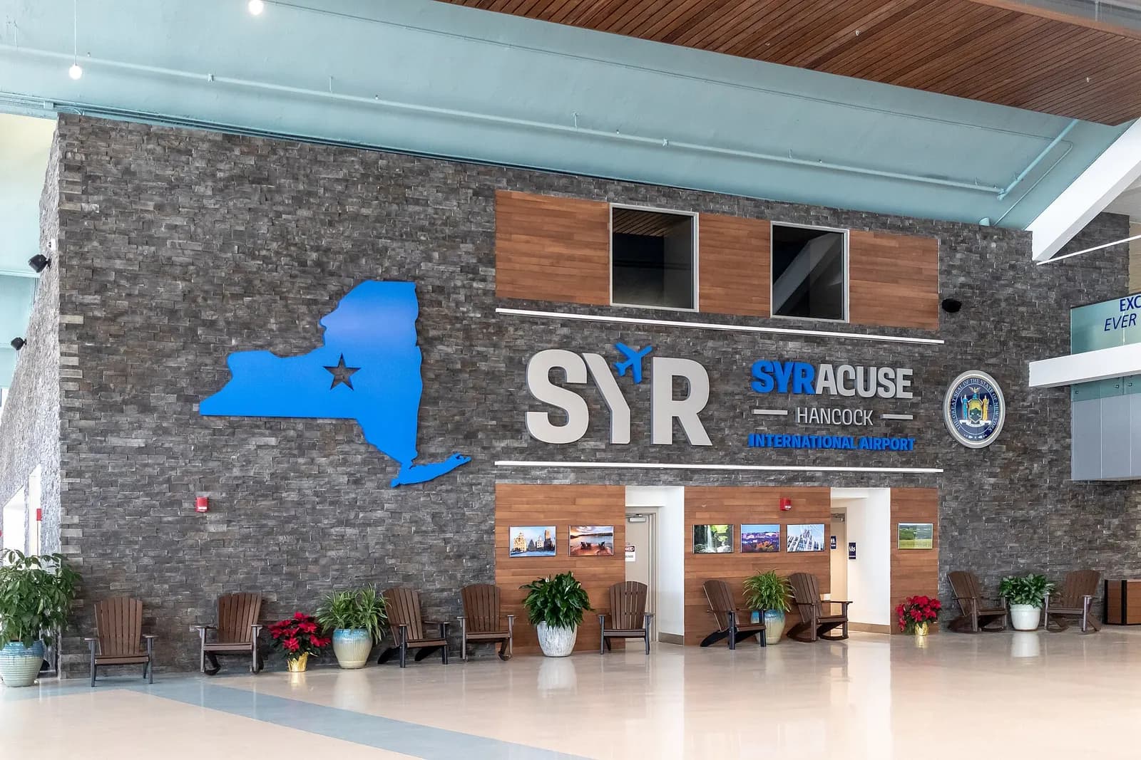 Blue Syracuse Hancock wordmark and New York State outline set into the rustic stone wall of the 2018 remodel.