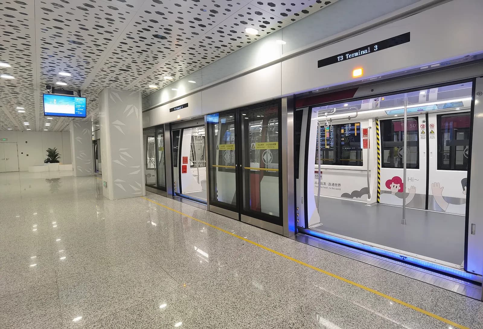 Shenzhen airport APM automated people-mover train at the Terminal 3 arrivals station platform with platform screen doors and route signage.