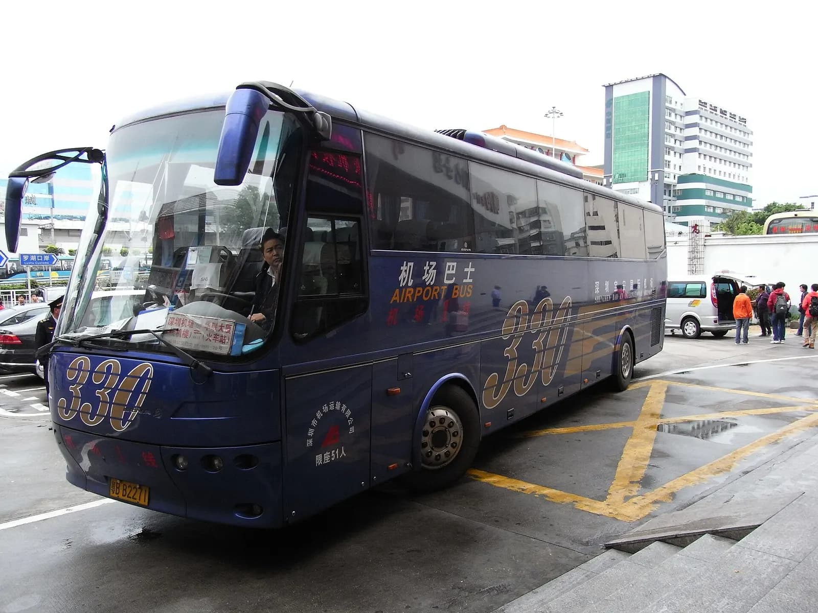 Blue Line 330 airport shuttle bus parked outside the Qiaoshe Bus Terminal in Shenzhen, with bilingual airport-route signage on its front.