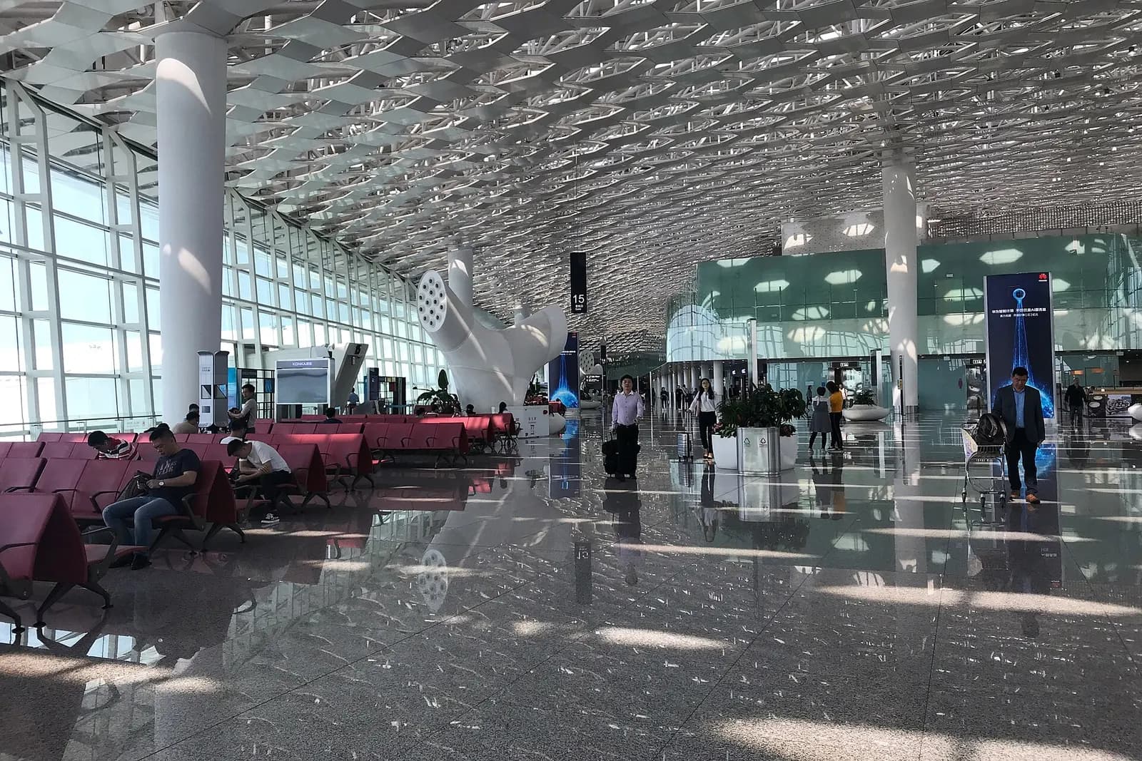 Airside waiting lounge in Terminal 3 with rows of seating, gate signage, and large windows overlooking the apron.