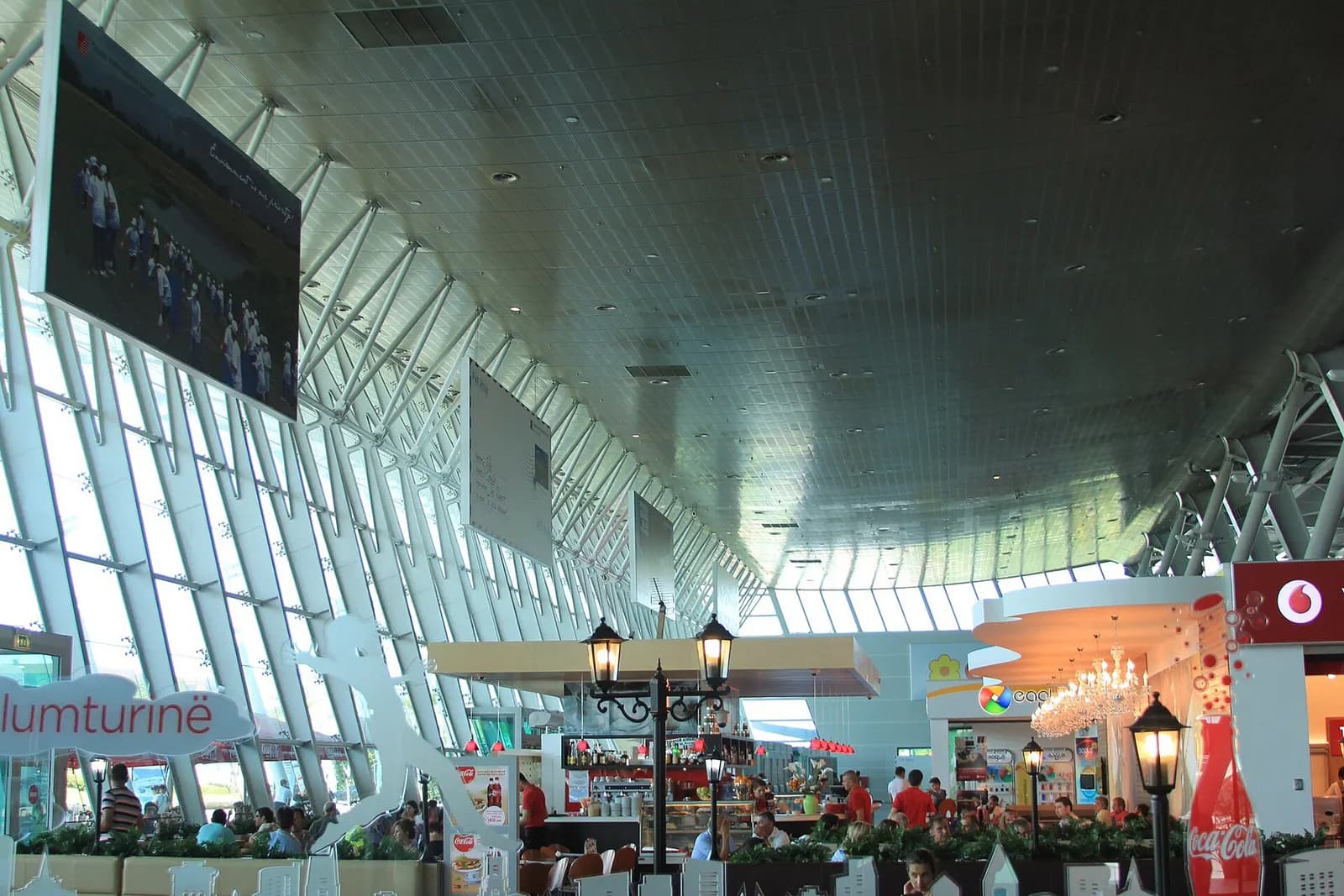 Interior seating and café area of Tirana International Airport under the glass curtain wall
