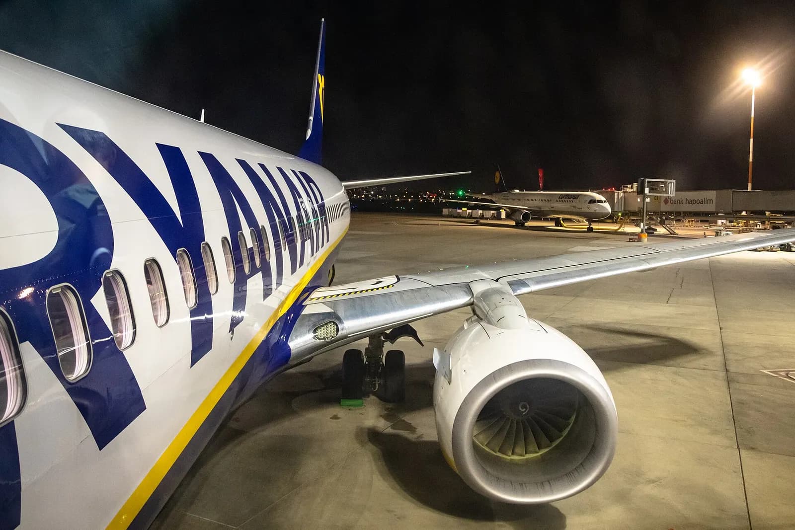Travelers climbing mobile stairs to board a Ryanair Boeing 737 parked on the tarmac at Ben Gurion Airport.
