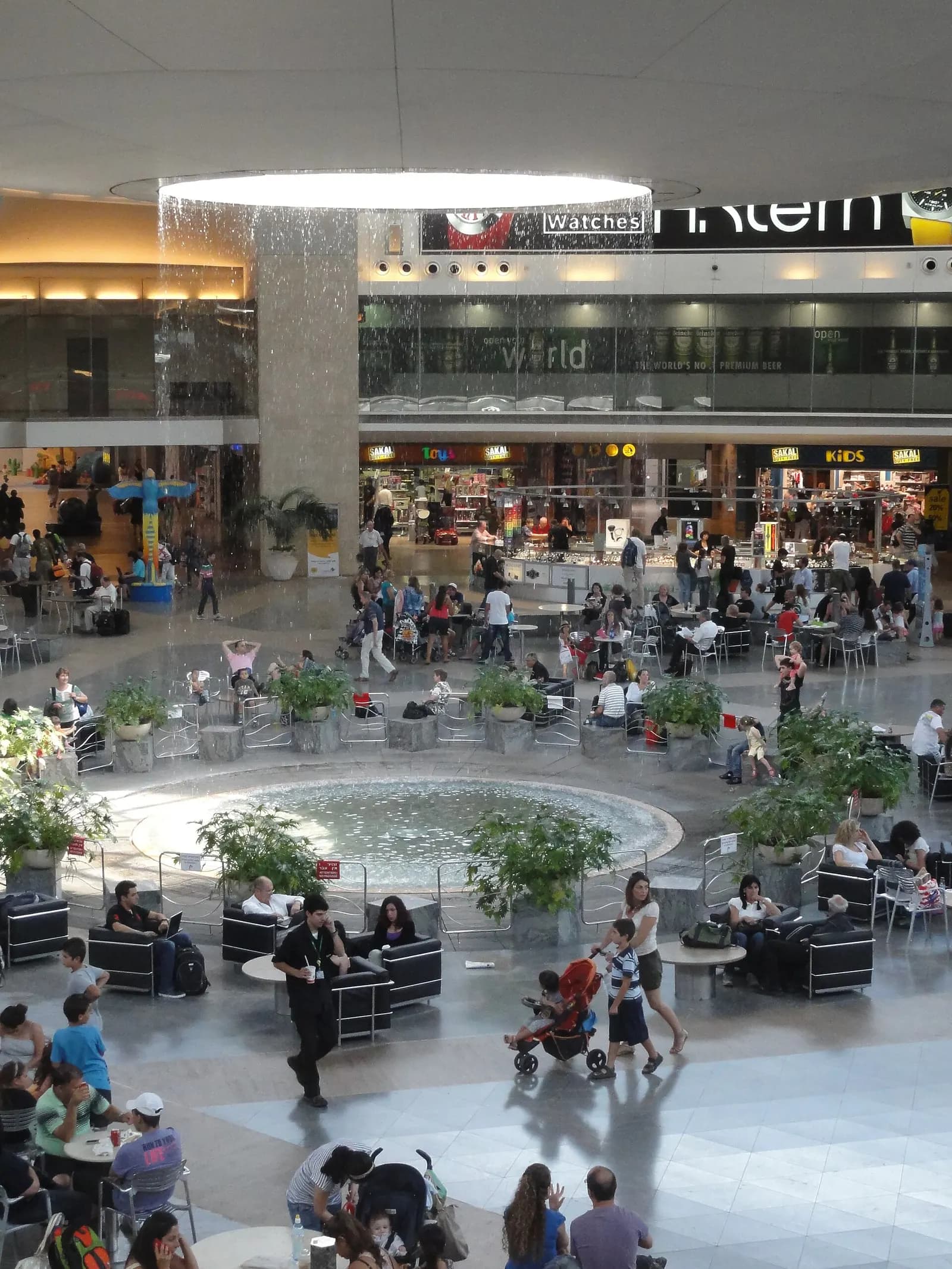 Inside Terminal 3's duty-free rotunda, where shoppers pass beneath a circular ceiling feature with water droplets falling from above.