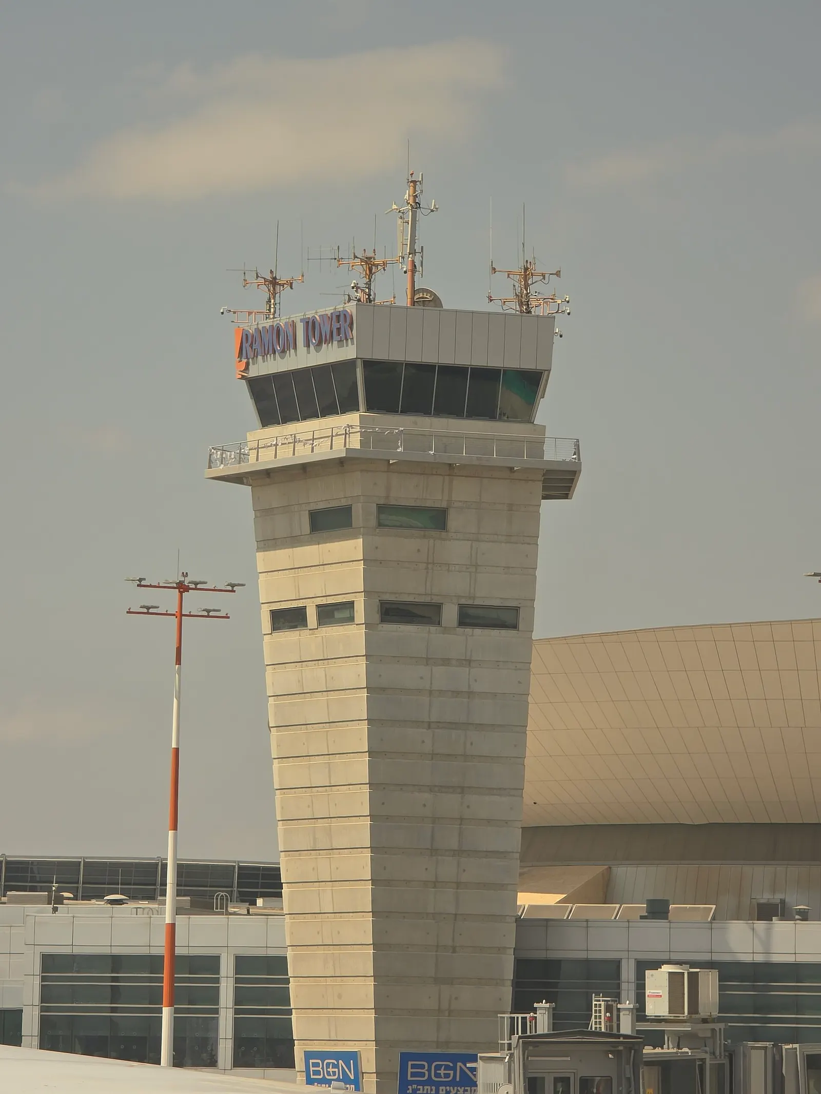 The tall, modern Ramon air traffic control tower rising above Ben Gurion Airport against a clear sky.