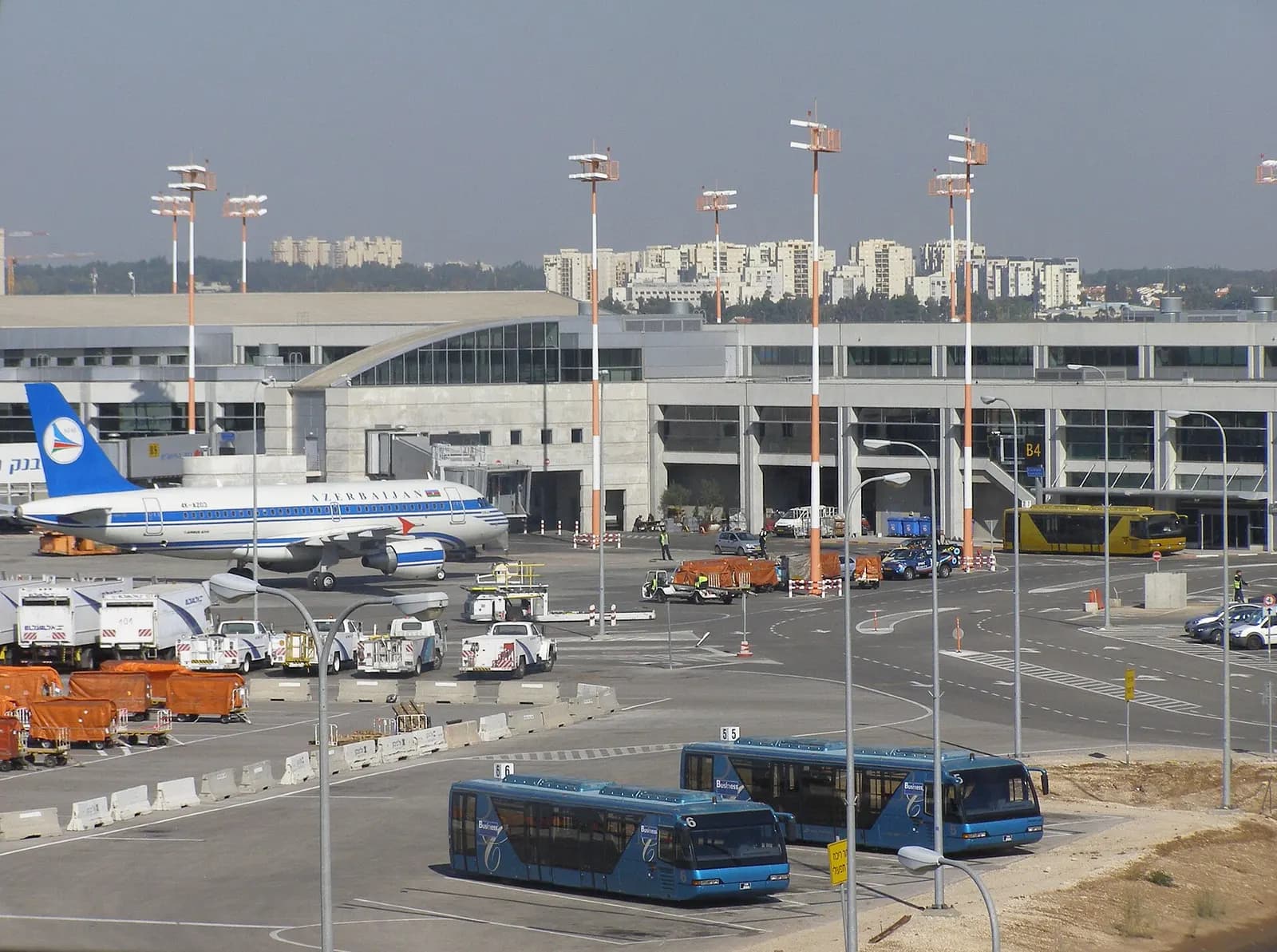Terminal 3's apron seen from the gate area, with blue VivAir shuttle buses parked in front of an Azerbaijan Airlines aircraft at the terminal building.