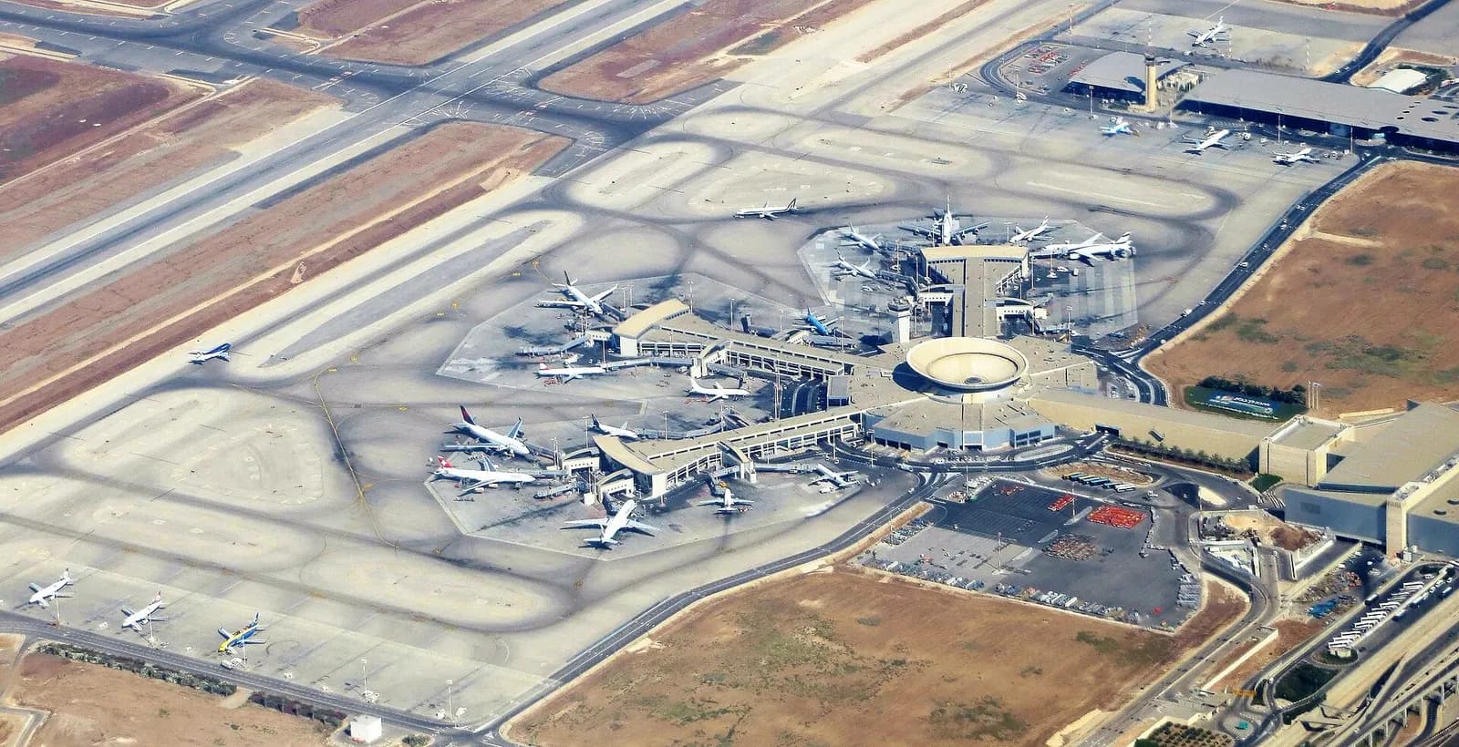 An aerial view of Ben Gurion Airport's Terminal 3 complex, runways, and surrounding countryside as seen from an overflying aircraft.