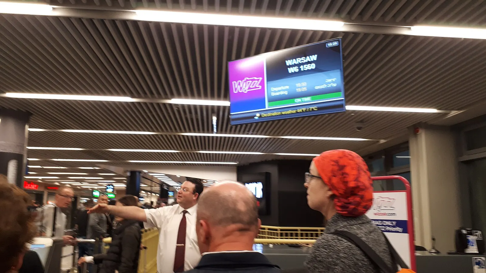 The departure hall of Ben Gurion Airport Terminal 1 with Wizz Air check-in counters and passengers queuing under a lower ceiling.