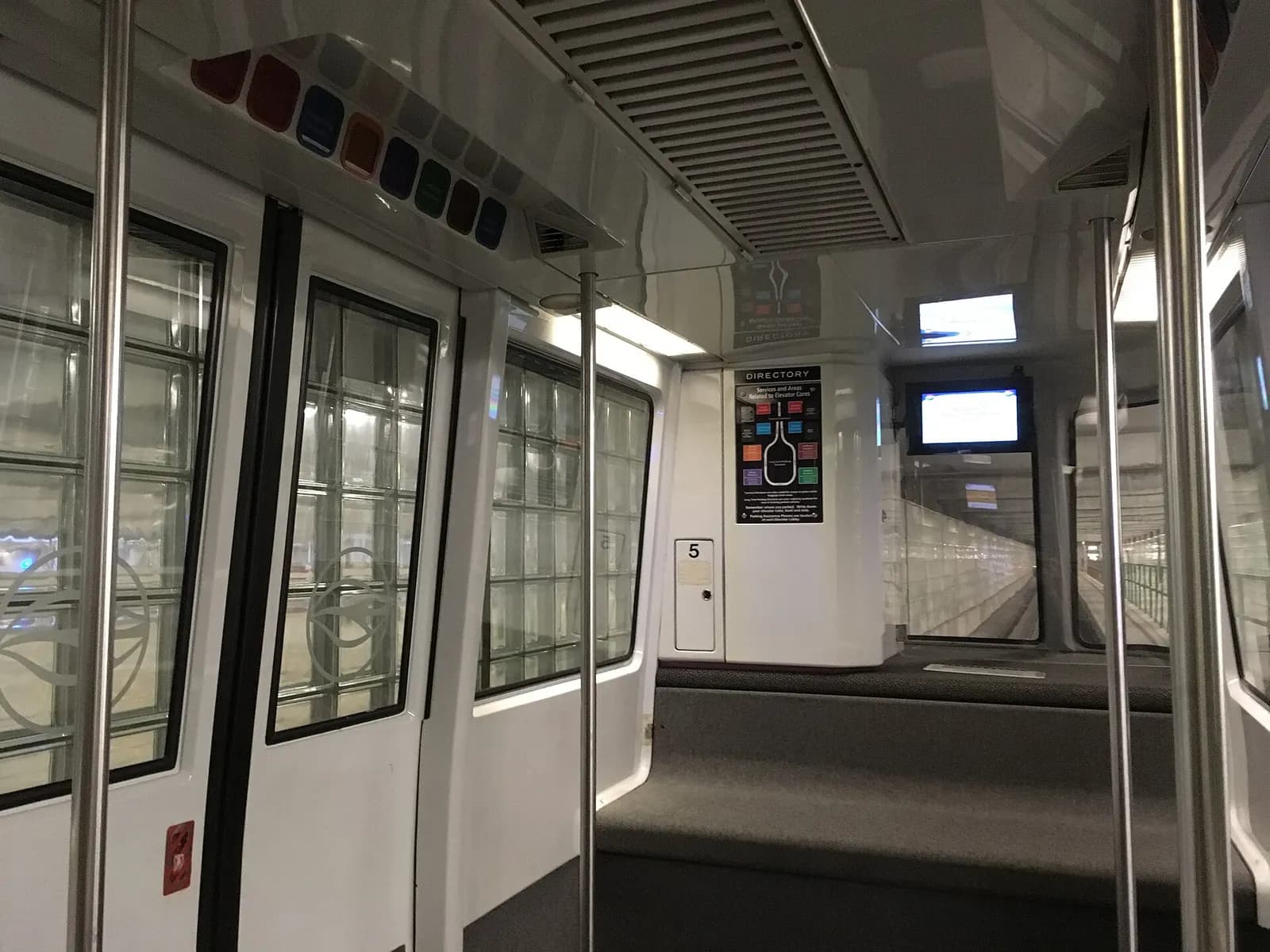 Interior of a monorail car inside Tampa International Airport's parking garage with rows of seats and handrails.