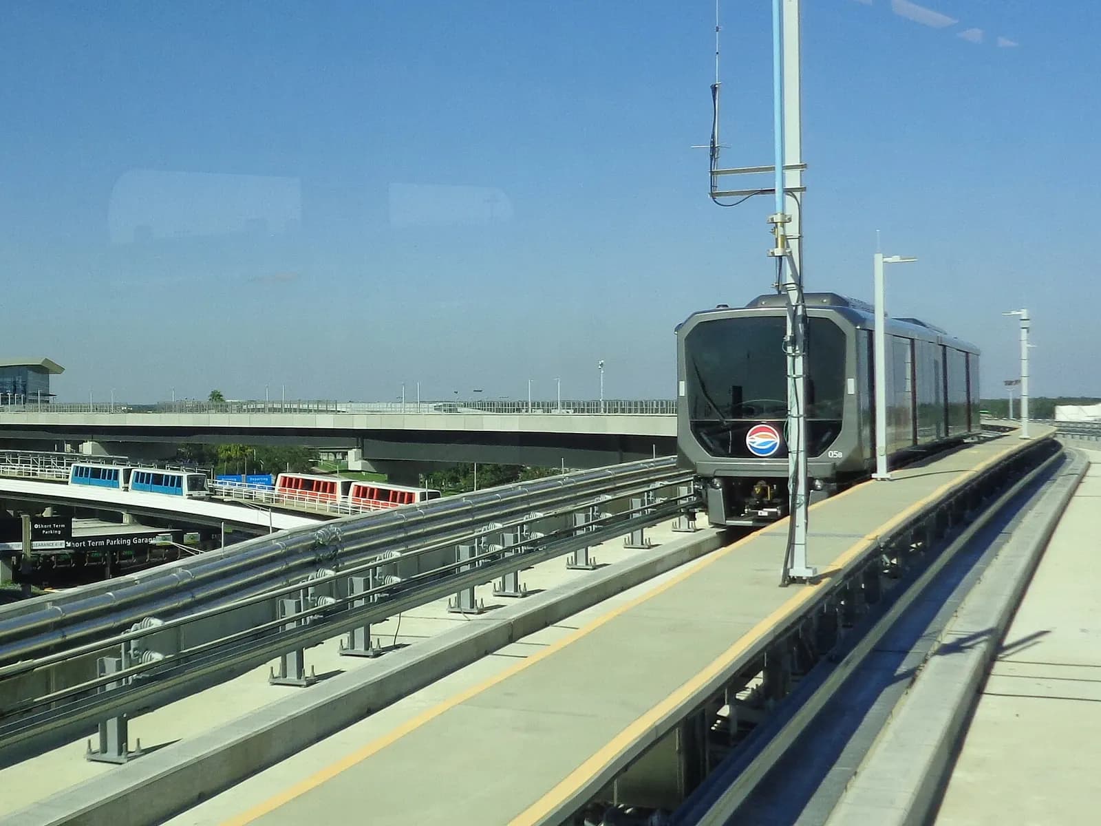 Elevated guideways for the SkyConnect people mover in the foreground and the Airside A shuttle line with a terminal building in the background.