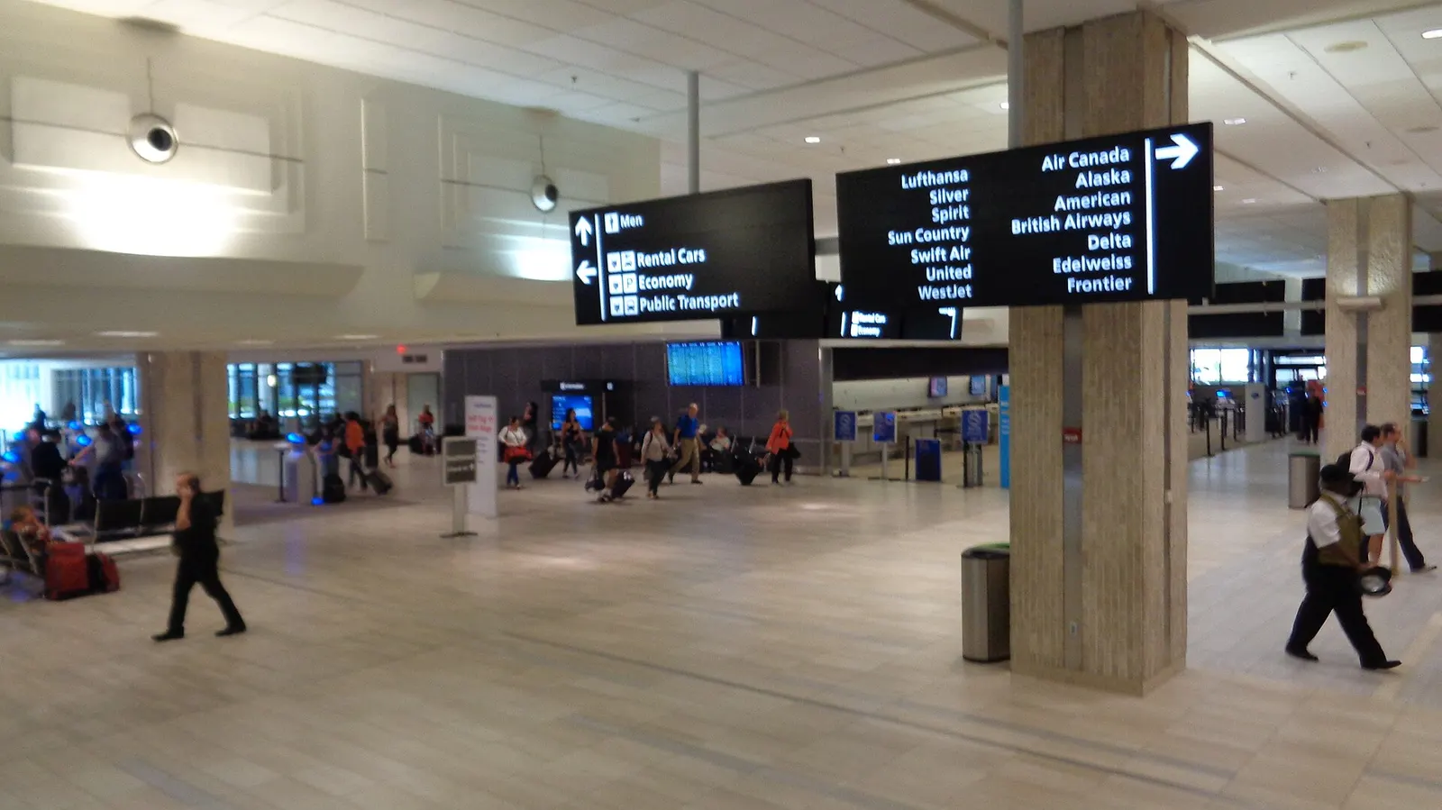 Wide interior view of Tampa International Airport main terminal Level 2 with airline ticket counters and travelers in the check-in hall.