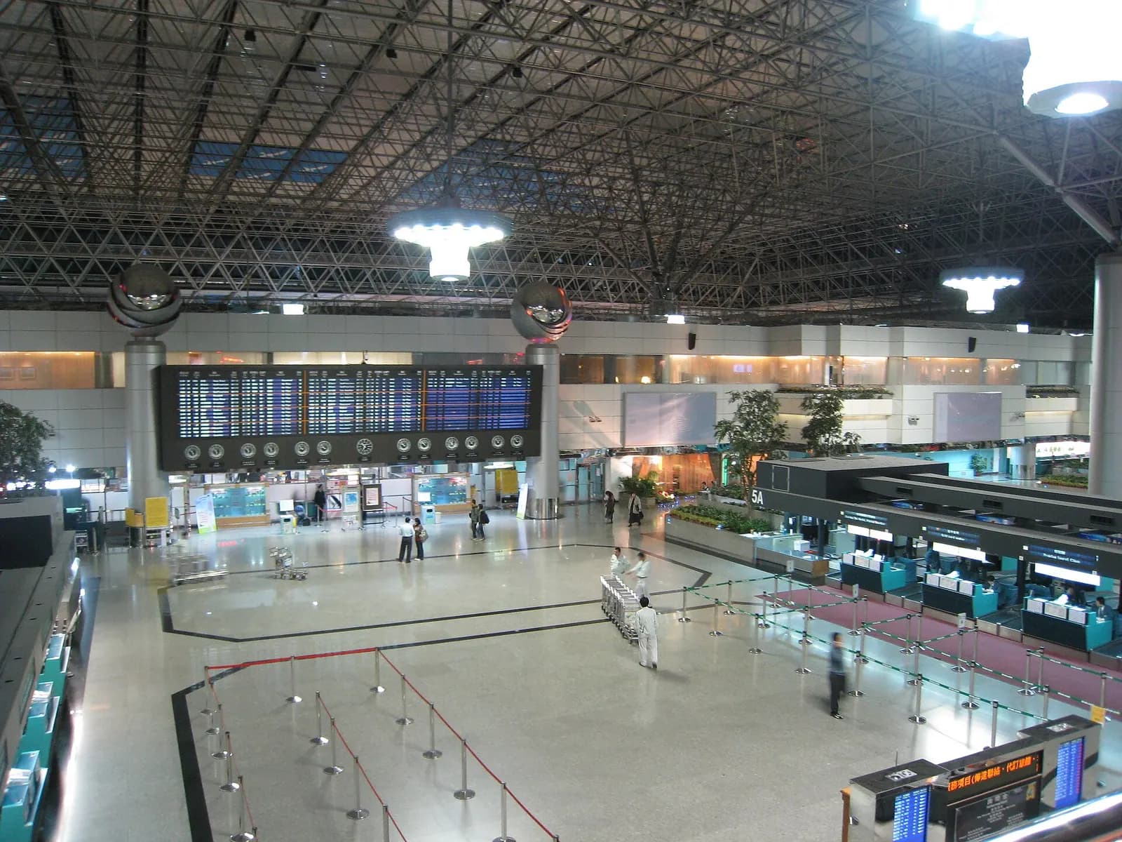 The Terminal 2 departure hall opens into a wide concourse with check-in islands, overhead signs, and passengers with luggage.