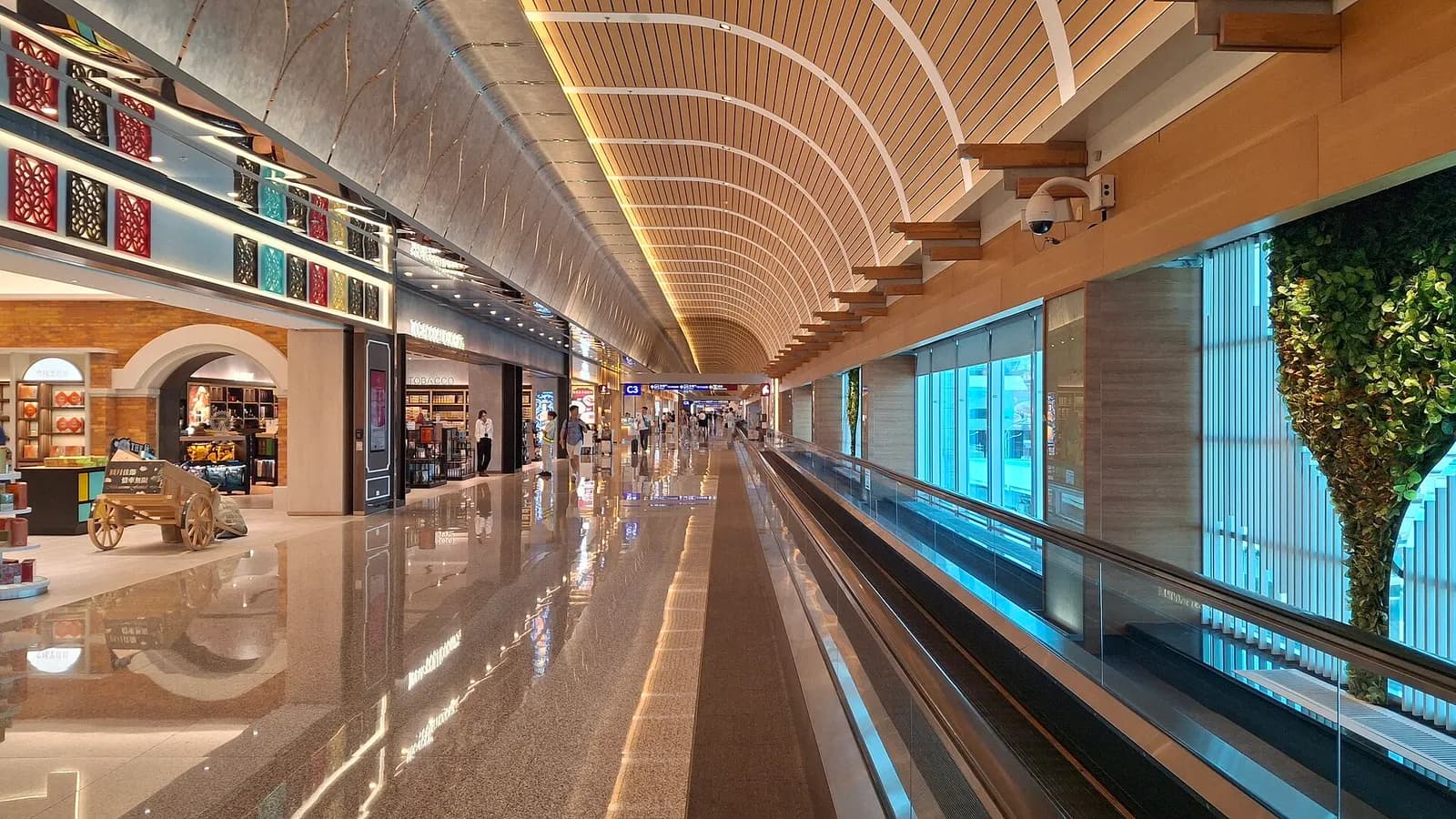 The exterior of Terminal 2 shows its multi-story glass-and-steel facade, entrance canopies, and the roadway in front.