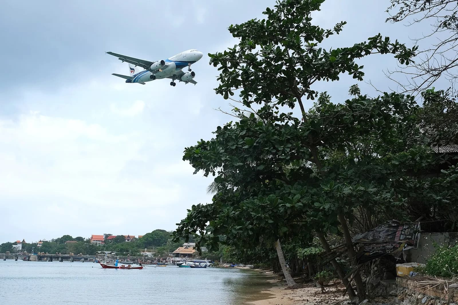 Bangkok Airways aircraft on the apron at Ko Samui Airport with terminal pavilions behind