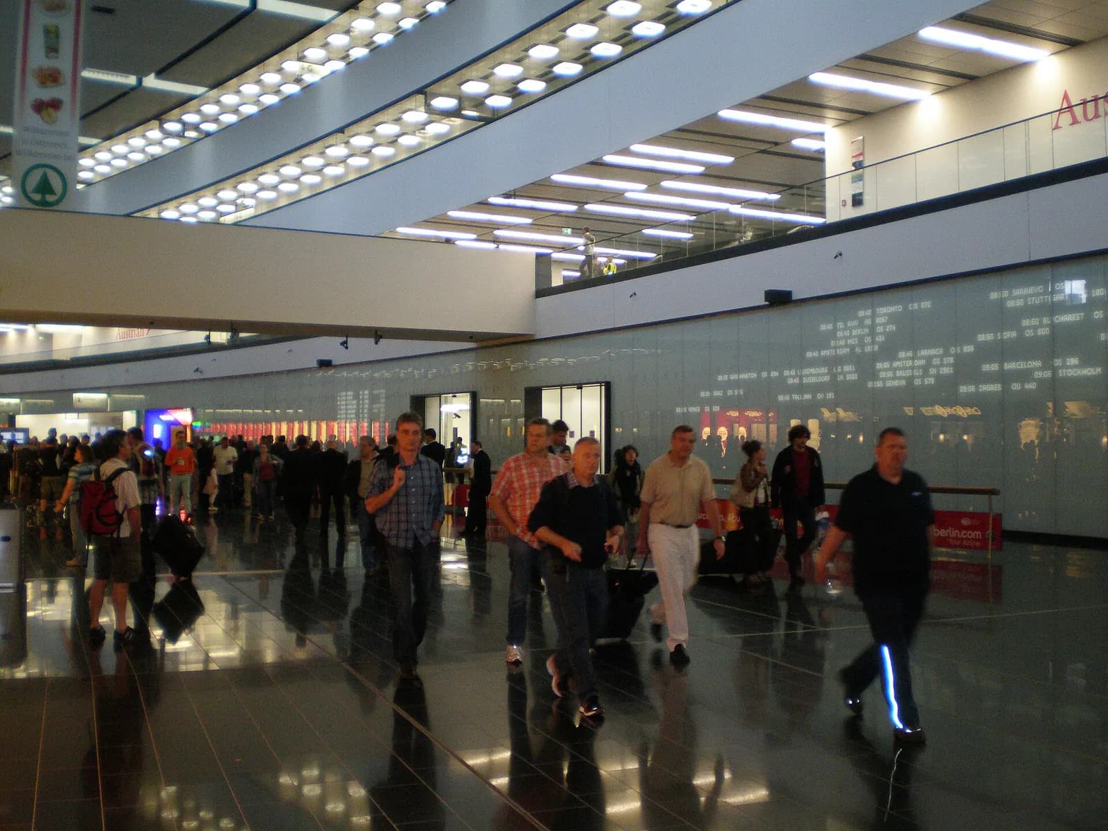 The ground-level arrivals hall with glass walls, directional signs, and passengers walking toward exits and ground transport.
