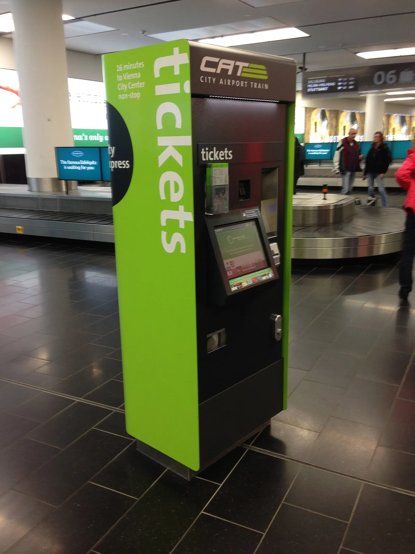 A City Airport Train (CAT) ticket vending machine in the airport terminal showing route maps and fare options on its screen.
