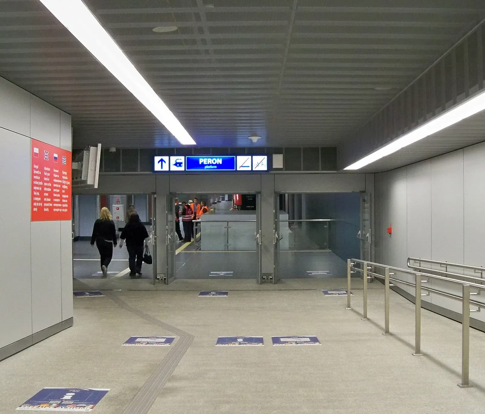 The street-level entrance to Warszawa Lotnisko Chopina railway station, with stairs, signage, and the station building facade.
