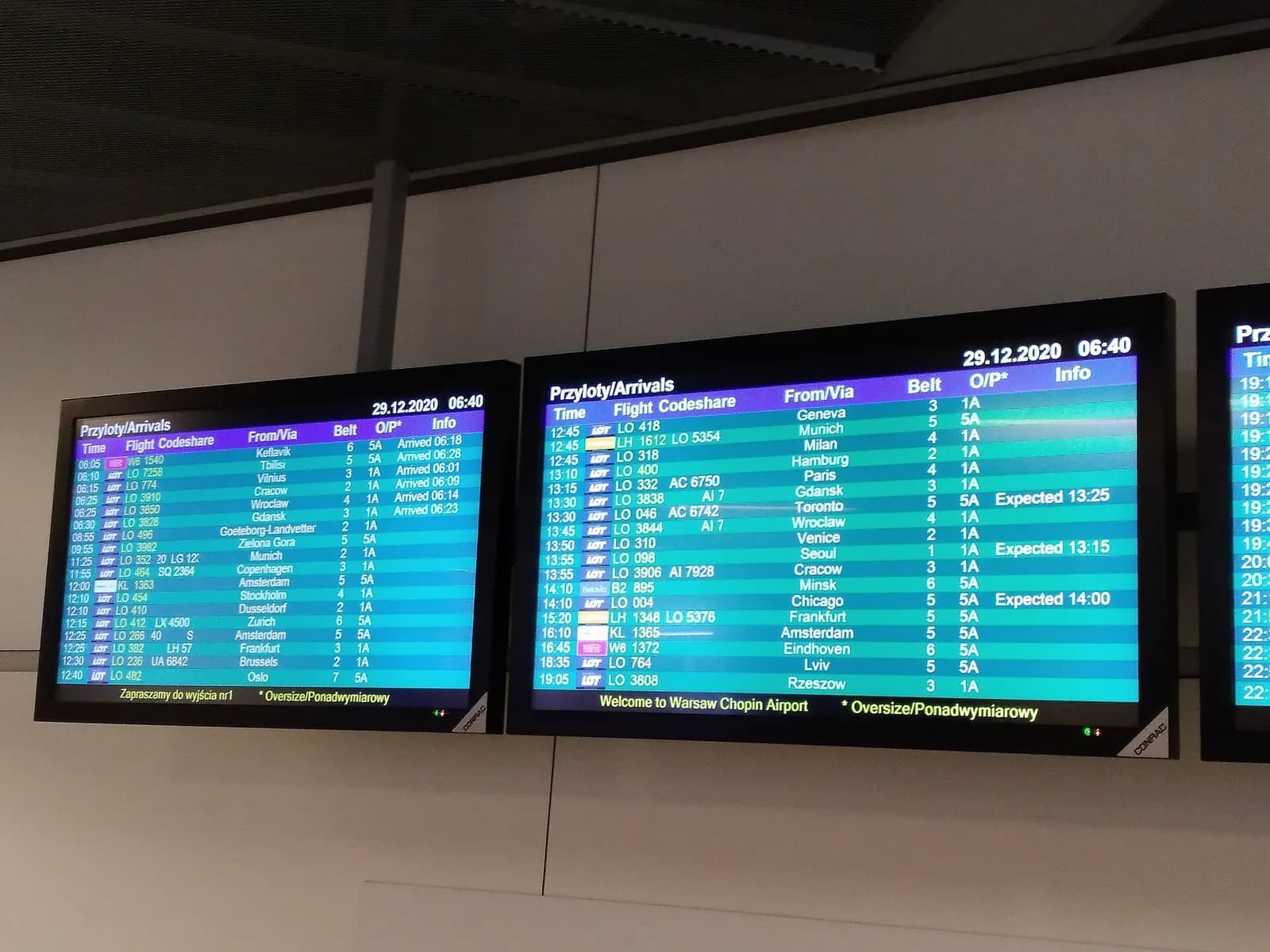 A large flight information display board listing departure and arrival times, gates, and airline names inside the terminal.