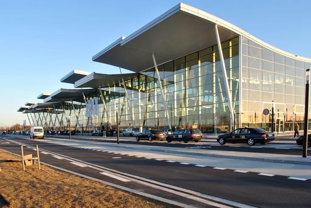 Exterior of Wrocław Airport Terminal T2 with glazed facade and roadway.