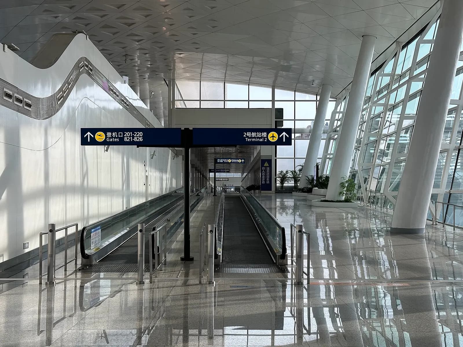 A post-security walkway inside the airport linking Terminal 3 to Terminal 2, with directional signs and moving walkways.