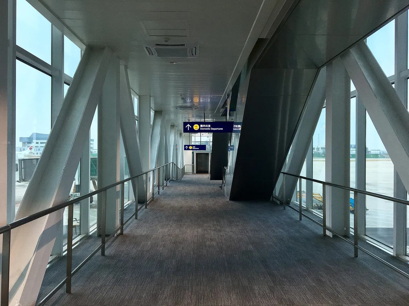 The enclosed passenger boarding bridge at Terminal 3, with windows overlooking the apron and an aircraft parked at the gate.