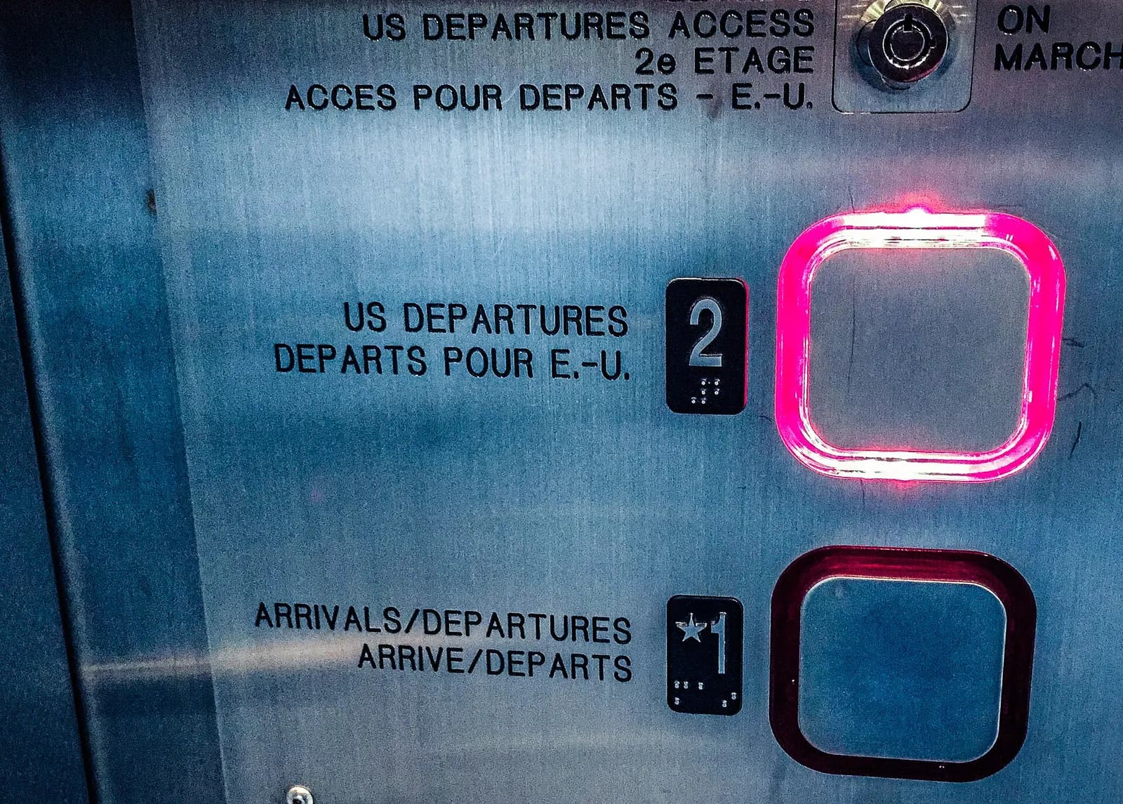Bilingual elevator panel: Level 2 US Departures / Départs pour E.-U., Level 1 Arrivals / Departures.