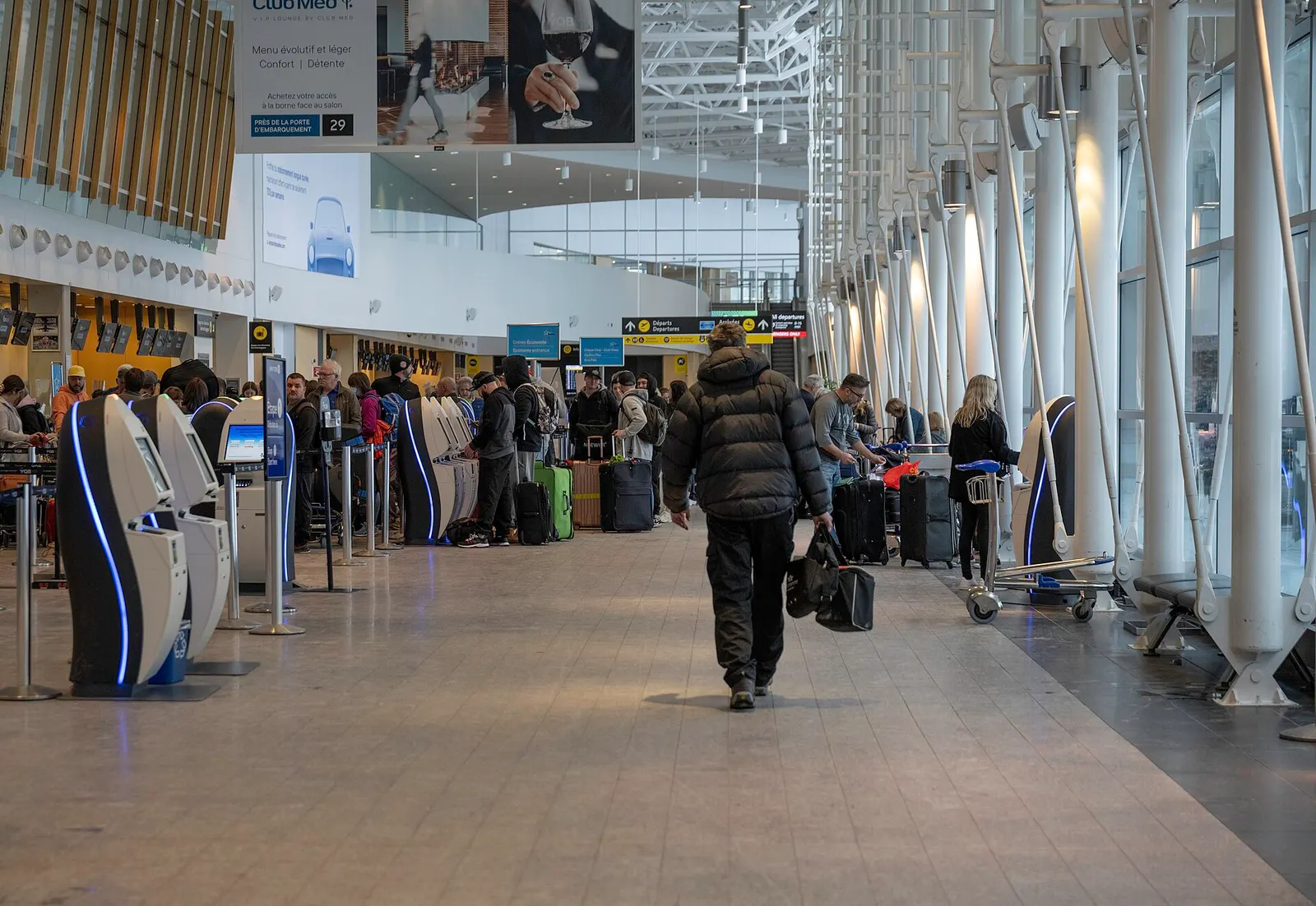 Self-serve check-in kiosks and queue stanchions in the YQB check-in hall