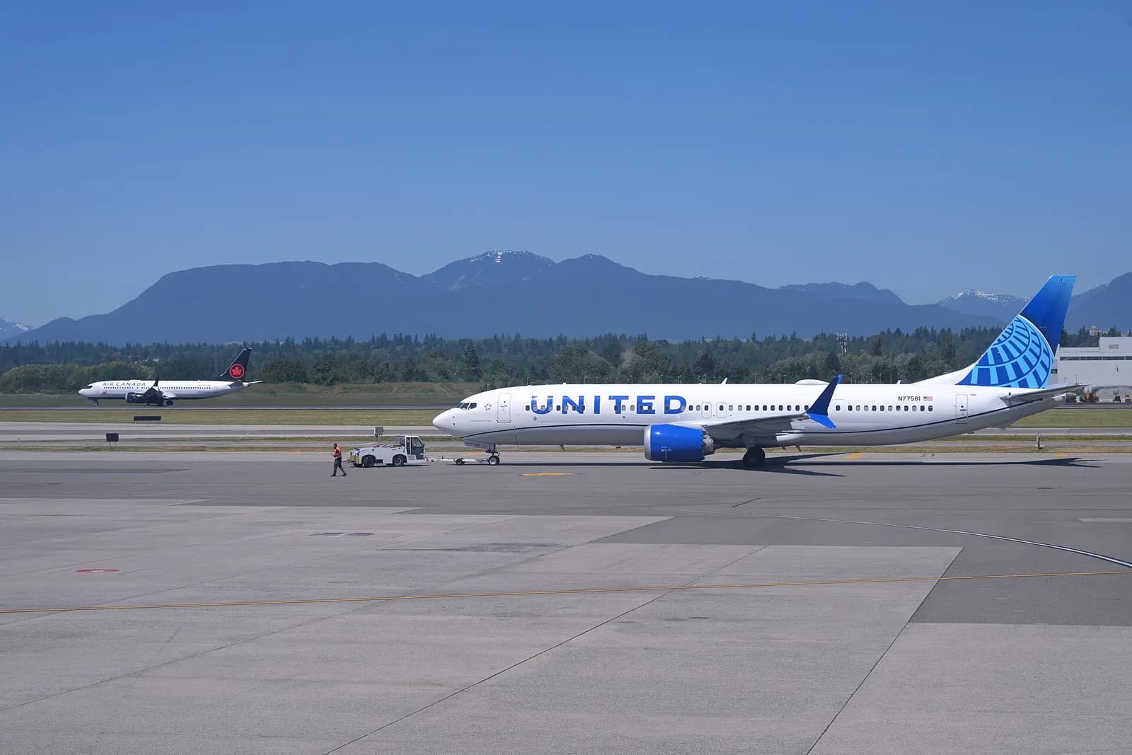 A Denver-bound United 737-9 MAX is pushed back while an Air Canada 737-8 MAX from Calgary lands at Vancouver International Airport.