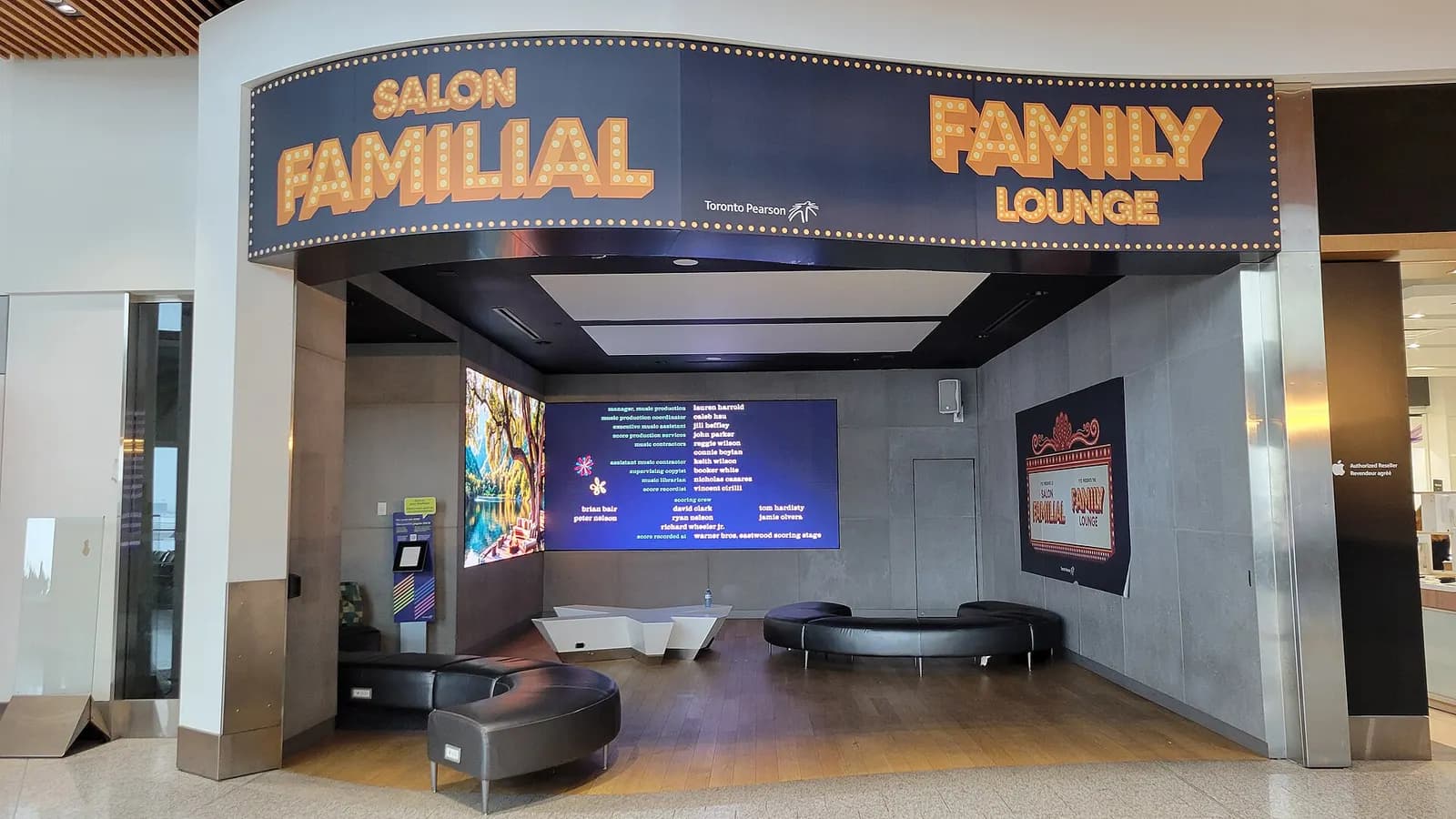 An airside family lounge in Terminal 1 has rows of seating facing a large screen playing a family-friendly movie.