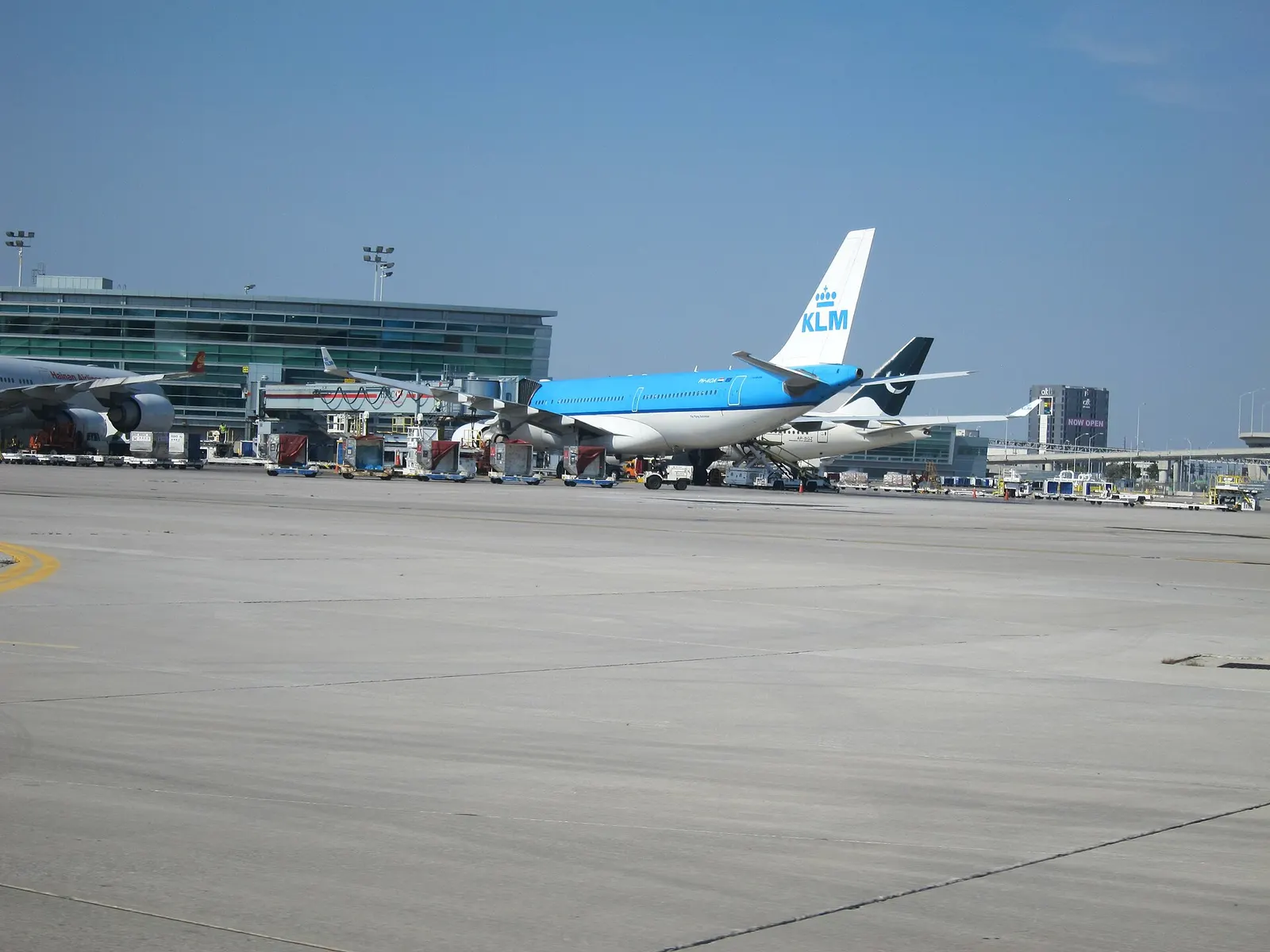 The Terminal 3 concourse shows airline signage, departure displays, and passengers moving through the wide indoor corridor.