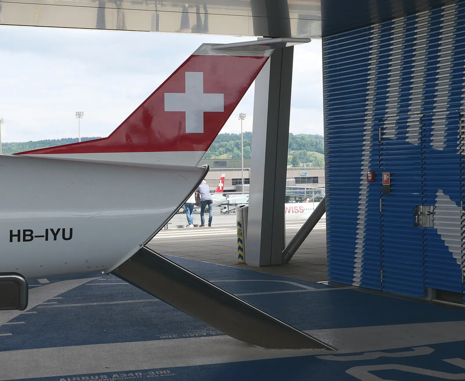 A children's playground on Observation Deck B with a Swiss aircraft-themed slide and a real Swiss aircraft visible on the apron behind it.