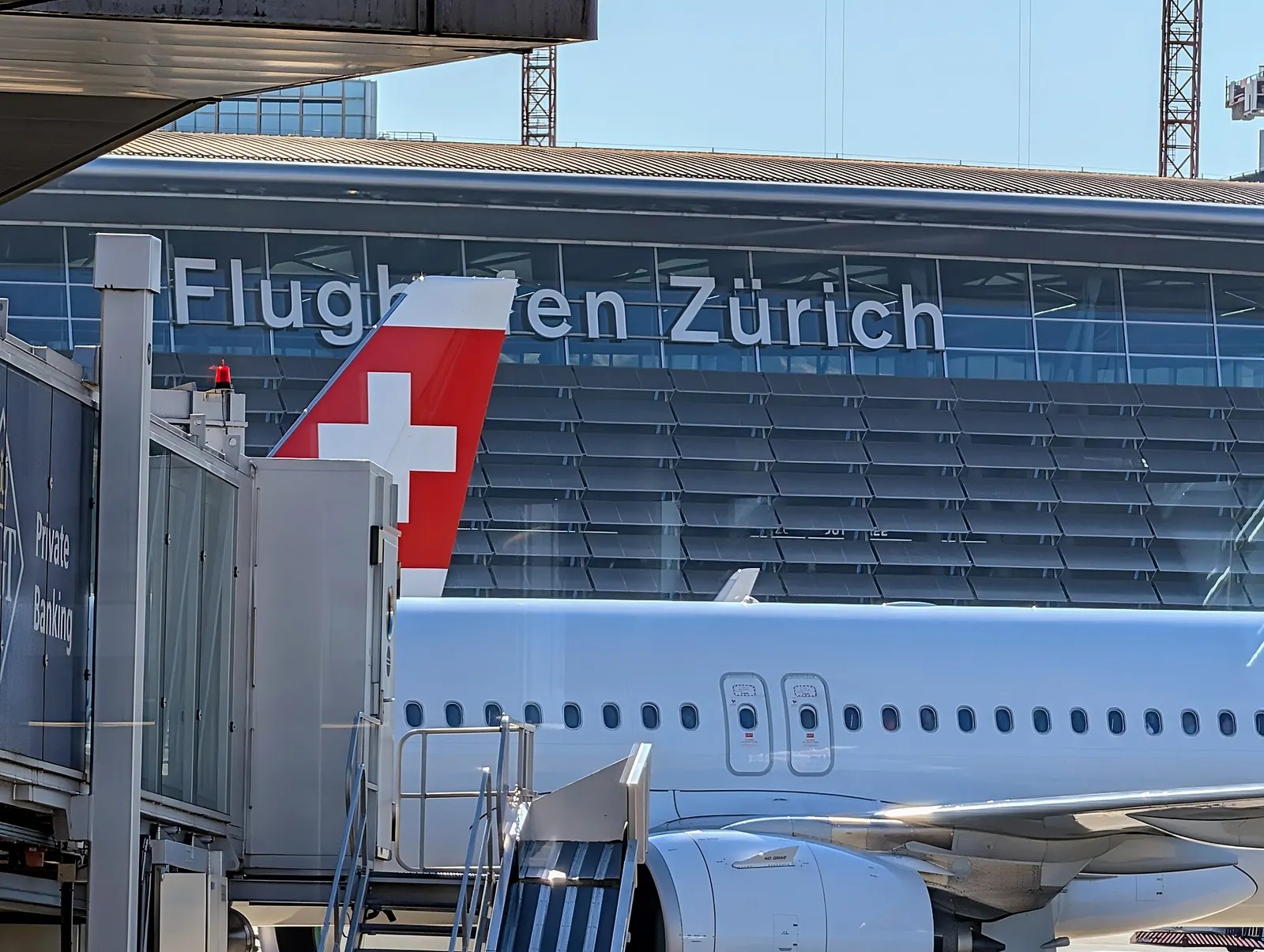 Swiss International Air Lines aircraft parked on the ramp in front of a large Flughafen Zürich airport sign and terminal buildings.